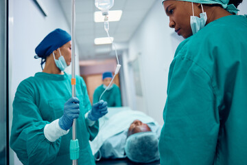 Female doctors taking patient out of operating room in hospital.