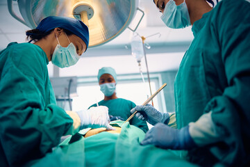 Female doctor performing surgery in operating room at medical clinic.
