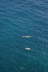 Two people canoeing and stand-up paddle boarding on blue water 