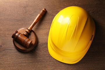 Law concept. Gavel and yellow hard hat on wooden table, top view