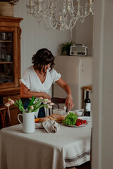 Beautiful girl with dark hair in the kitchen with wine and food