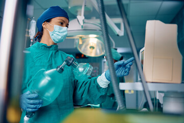 Female anesthesiologist looking at monitor in operating room in hospital.