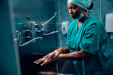 Black female surgeon disinfecting her hands before the surgery.