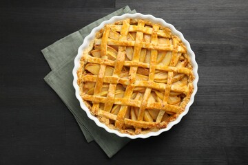 Tasty homemade quince pie on black wooden table, top view
