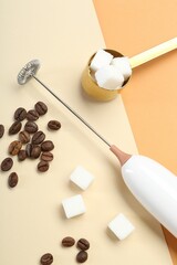 Milk frother wand, coffee beans and sugar cubes on color background, flat lay