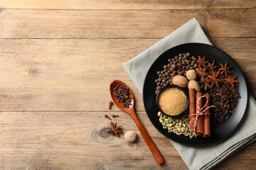 Dishware with different spices on wooden table, flat lay. Space for text