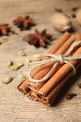 Cinnamon sticks and other spices on wooden table, closeup