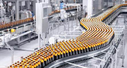 Brown glass beer bottles on conveyor belt Automated brewery industry manufacturing with sunlight