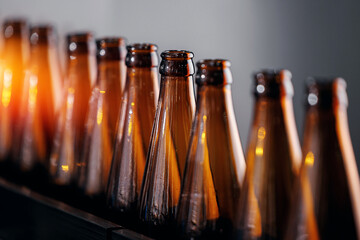 Beer brewery industry manufacturing. Brown glass bottles on conveyor belt with sunlight