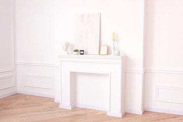a white fireplace on a white wall with decor. a fake fireplace in the photo studio for a wedding photo shoot. bright classic photo zone