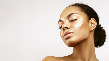 African American skincare model portrait with a glowing hydrated skin and cream smear on her face. Beauty spa treatment concept.Young girl posing with closed eyes against grey background - obrazy, fototapety, plakaty