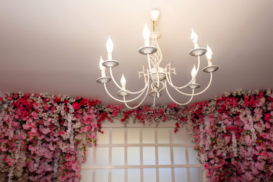chandelier on the background of a wooden frame with sakura flowers. wedding photo zone in the photo studio with pink flowers. artificial flowers chandelier and wooden lattice