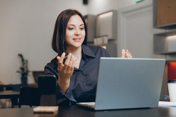 Emotional conversation of young woman on video call through laptop. Lifestyle workplace in cafe.