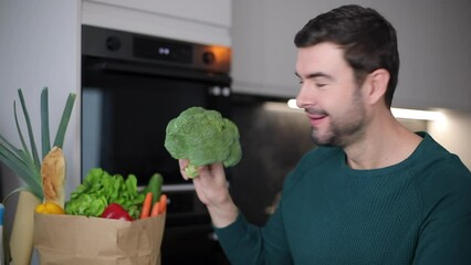 Man eating a raw broccoli 