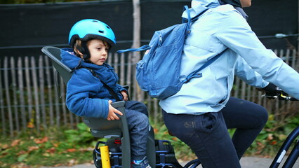 Fototapeta na wymiar Mother Cycling with Child in Backseat Wearing Helmet, Autumn Bike Ride