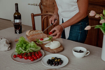 Close-up of hands preparing snack sandwich and wine in kitchen