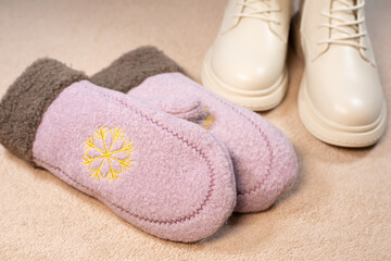 Beige winter women's leather boots and Cute pink mittens. Beautiful modern Clothes for cold weather wearing. Romantic Present for girl on Saint Valentine day.