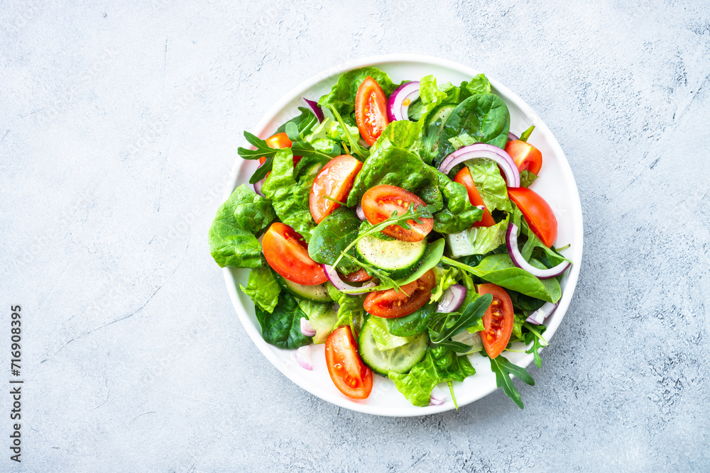 Poster Fresh green salad with leaves and vegetables. Top view with copy space at stone table.