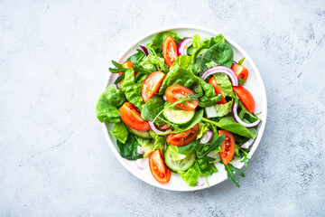Fresh green salad with leaves and vegetables. Top view with copy space at stone table.
