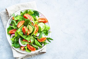 Green salad with leaves and vegetables. Vegan food, diet meal. Top view with copy space at stone table.