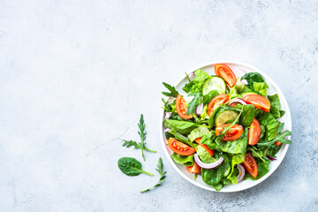 Green salad with leaves and vegetables. Vegan food, diet meal. Top view with copy space at stone table.