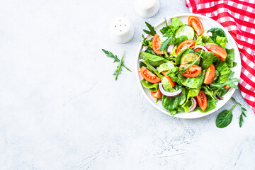 Green salad with leaves and vegetables. Vegan food, diet meal. Top view with copy space at stone table.