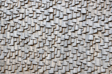 Gray wooden roof tiles background texture. A close up of old gray roof covered with wooden tiles or shingles