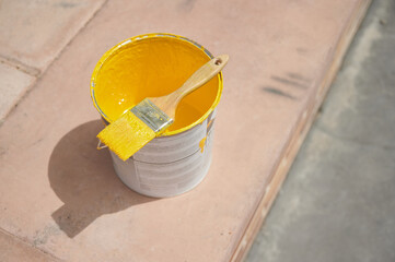 Paint brush on a yellow paint bucket ready to apply special acrylic paint for road marking on...