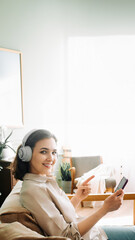 Fototapeta na wymiar Happy Young Woman with Wireless Headphones Smiles, Points to Smartphone, Reading a Message. Joyful Young Woman with Wireless Headphones, Smiling, and Pointing at Smartphone While Reading a Message