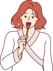 Woman uses tongue brush to clean mouth from germs, showing example of hygiene education