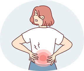 Woman stands with back to screen and holds on to red lower back after failing to lift heavy bag. Girl suffers from pain in spine needs massage or help of osteopath doctor.