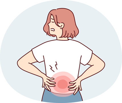 Woman stands with back to screen and holds on to red lower back after failing to lift heavy bag. Girl suffers from pain in spine needs massage or help of osteopath doctor.