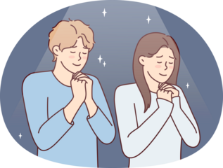 Positive man and woman praying asking god for happy marriage. Young couple stand with eyes closed and clasping palms in front of chest together performs religious ritual