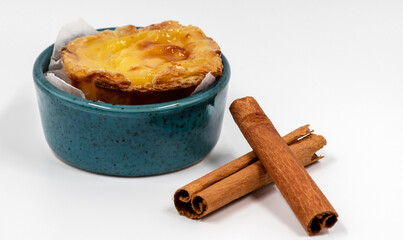Pastel de nata tarts or Portuguese egg tart and cinnamon sticks isolated on white background. Pastel de Belem is a small pie with a crispy puff pastry crust and a custard cream filling.