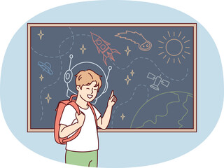 Joyful boy stands near blackboard depicting universe with spaceships and planets. Vector image