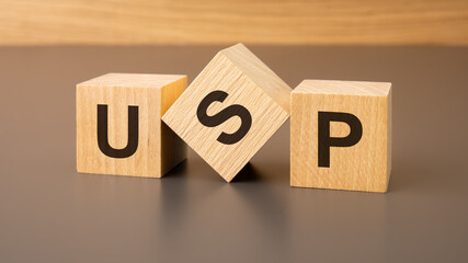 three wooden blocks on a brown background, with the abbreviation USP - Unique Selling Proposition