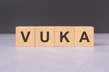 Wooden cubes align to spell VUKA, embodying the issue of unwanted communication