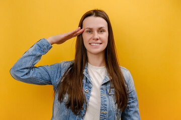 Portrait of cute young woman standing saluting with hand near head, looking obedient and attentive...
