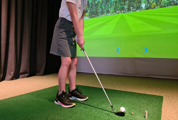 Teen girl playing in a golf simulator indoors