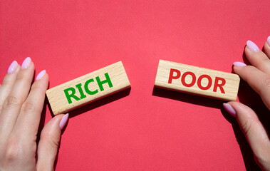 Rich vs Poor symbol. Concept word Rich vs Poor on wooden blocks. Businessman hand. Beautiful red background. Business and Rich vs Poor concept. Copy space