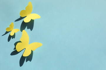 Yellow paper butterflies on turquoise background, top view. Space for text