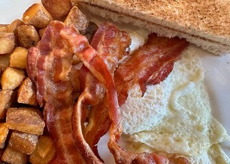 Fried, over easy eggs, bacon, hash browns, and toast