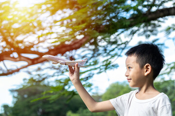 Cute Asian child playing airplane in the park outdoors Happy Asian boy holding a plane runs in a...