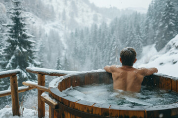 Back view of a man relaxing in a wooden outdoor ice bath amidst Winter forest covered in snow,...