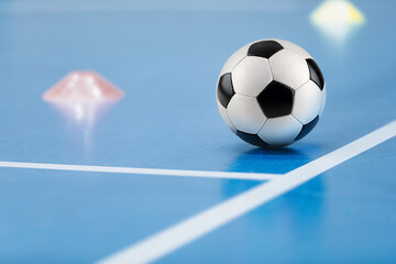 Futsal practice pitch. Indoor soccer ball and training equipment on blue futsal floor. Football...