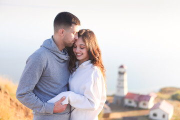 Romantic couple dressed in cozy sweaters together near the lighthouse