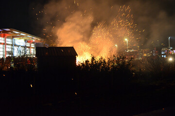 Riesiger Funkenflug aus dem qualmenden Feuer vor der Feuerwache mit dicker Rauchwolke. Scharfer...