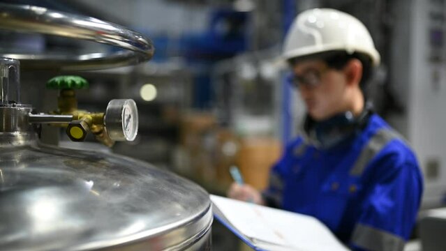 Asian engineer working at Operating hall,Thailand people wear helmet  work,He worked with diligence and patience,she checked the valve regulator at the hydrogen tank.