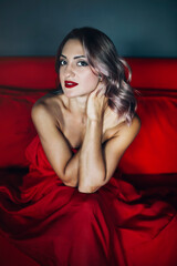 Fototapeta premium Alluring woman sitting on red sofa