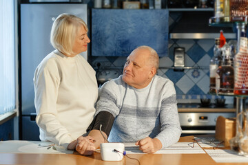 Fototapeta premium An elderly woman measures her husband's blood pressure and pulse.